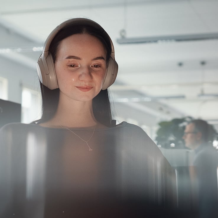 Kvinne med headset i kontorlandskap